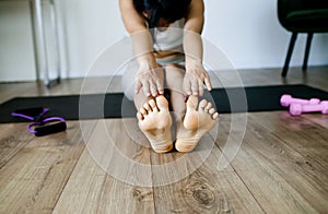 Woman Sitting Barefoot Stretching Her Back And Legs .