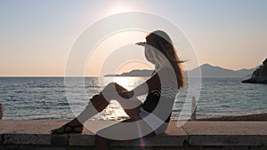 Woman Sitting On Beach Looking Into Distance With Hand Of The Eye From The Sun