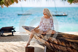 Woman sitting on the beach near the boat. photo