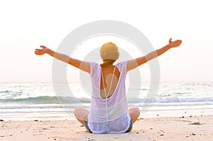 woman is sitting on beach at sunrise