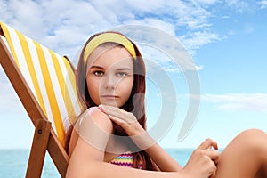 Woman sitting at the beach you put the sunscreen