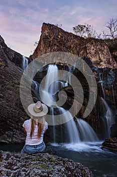 Woman sitting by a beautiful mountain waterfall