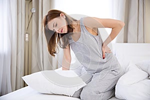 Woman sitting on the bed with back pain