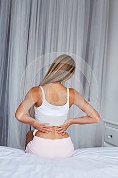 Woman sitting on a bed with back pain