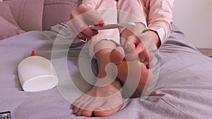 Woman sitting in bed and doing pedicure
