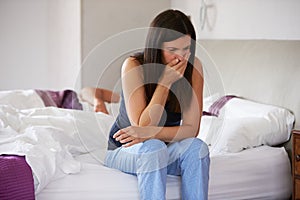 Woman Sitting On Bed And Feeling Unwell photo