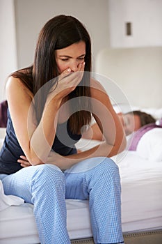 Woman Sitting On Bed And Feeling Unwell