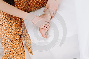 Woman sitting on the bed massages her foot, close-up