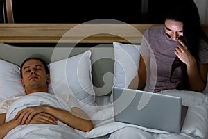 Woman sitting on bed in the night and using laptop computer