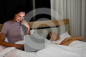 Woman sitting on bed in the night and using laptop computer