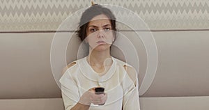 woman sitting on the bed and watching TV using remote control