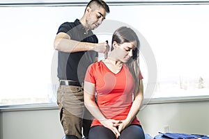 Woman sitting while being massaged by a man in room