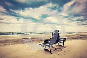 Woman sitting on a bench on the beach using her phone