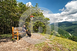 Woman sitting on bench and her dog bandog on top of the hill Cipcie in Slovakia