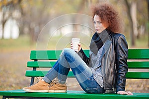 Woman sitting on the bench and holding cup with coffee