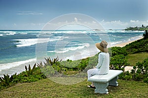 A Woman Sitting on a Bench Overlooking the Sea