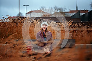 Woman sitting on the bench watching yellow leaves tree in autumn.