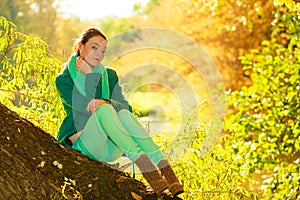 Woman sitting on big tree trunk