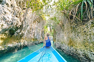 Woman sitting on boat in narrow canyon and turquoise lagoon at Bair Island, tropical paradise pristine coast rainforest blue sea.