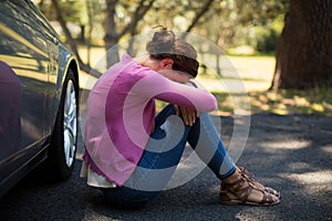 Woman sitting by breakdown car