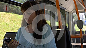 Woman sitting on the bus and listening to music from phone