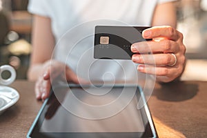 Woman sitting in cafe and holding credit card in hand