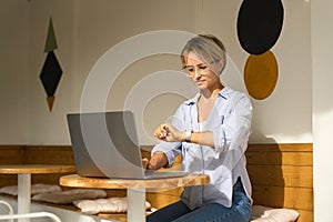 Woman sitting at cafe table and working on laptop computer. Female surfing internet on laptop using cafe wifi.