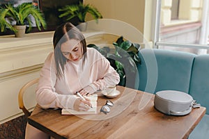 Woman sitting in a cafe writes in a diary