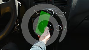 Woman sitting in car and attach her phone with vertical green screen.