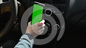 Woman sitting in car and attach her phone with vertical green screen