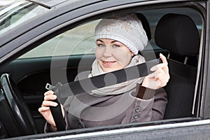 Woman sitting in car and holding seat belt