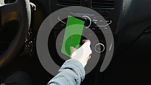 Woman sitting in car and using her phone with vertical green screen