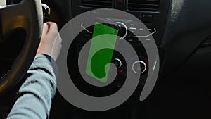 Woman sitting in car and using her phone with vertical green screen