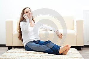 Woman sitting on carpet and talking by phone