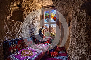 Woman sitting in cave house and looking to windows with beautiful scenic in Goreme, Cappadocia, Turkey. photo