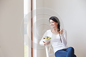 Woman Sitting In Chair Eating Bowl Of Fresh Fruit