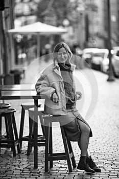 Woman sitting on a chair outside a sidewalk cafe, Porto, Portugal. .
