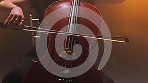 Woman sitting on chair while playing on cello during concert