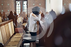 Woman sitting with clasped hands in church