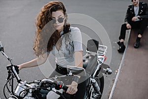 woman sitting on classical cruiser motorcycle while her boyfriend
