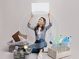 Woman Sitting Among Containers With Different Sorted Garbage And Holding White Placard