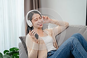 A woman is sitting on a couch with a cell phone in her hand