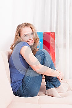 Woman sitting on couch feeling comfy and smiling