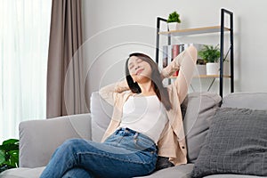 A woman is sitting on a couch with her arms crossed and a relaxed expression on her face