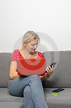 Woman is sitting on couch at home and paying online with smartphone