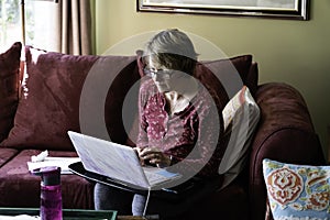 Woman sitting on couch at home working on a computer