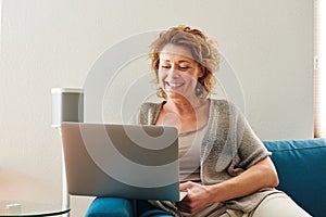 Woman sitting on couch with laptop at home
