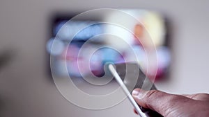 Woman sitting on the couch in living room with tv remote and watching VOD online streaming platform