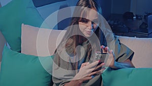 a woman is sitting on a couch looking at her cell phone