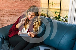 Woman sitting on couch with pen and textbook